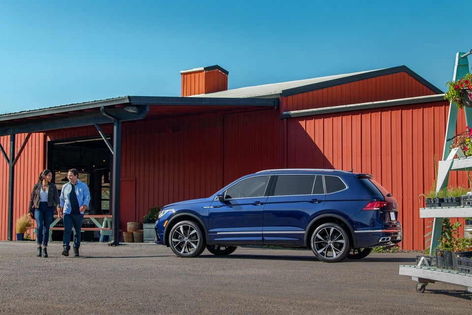A man and woman standing near a Volkswagen Tiguan